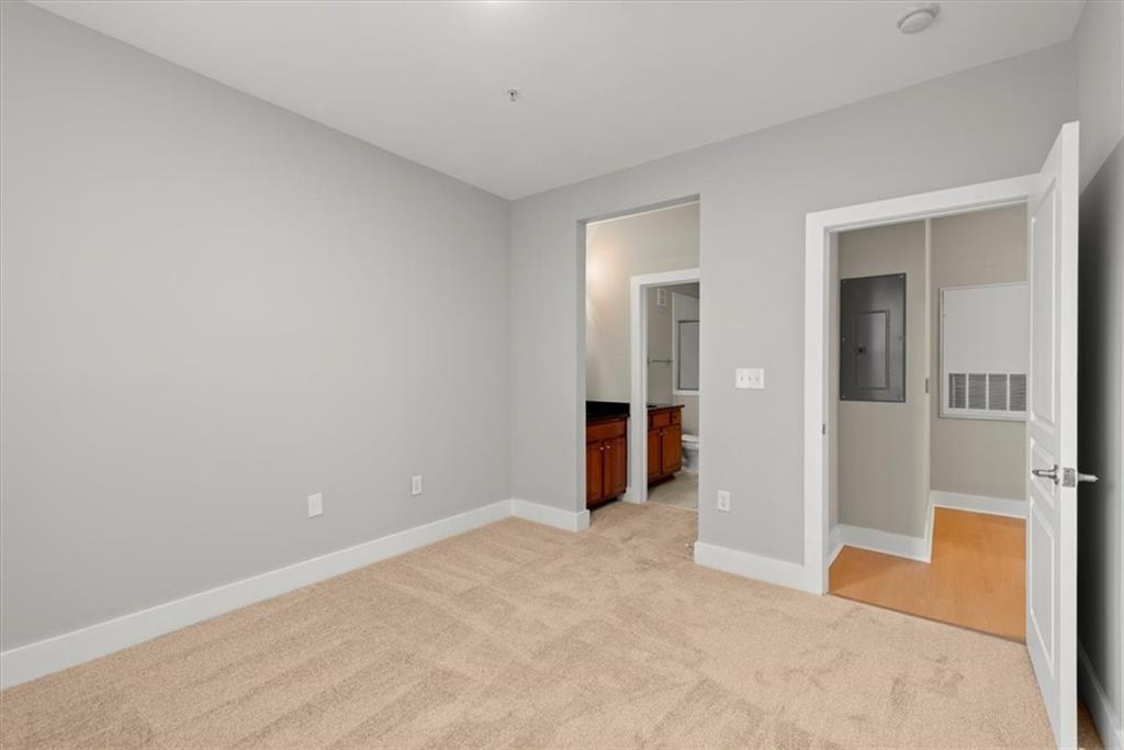 Unfurnished bedroom featuring ensuite bathroom and light colored carpet