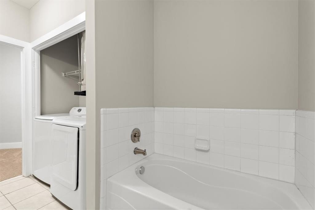 Bathroom with tile floors, a bath, and washer and clothes dryer
