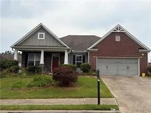 Brick and siding exterior with a covered porch featuring white columns, a two-car garage, and a concrete driveway