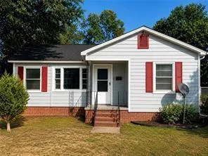 Siding exterior with red shutters, brick foundation, and a gabled roof