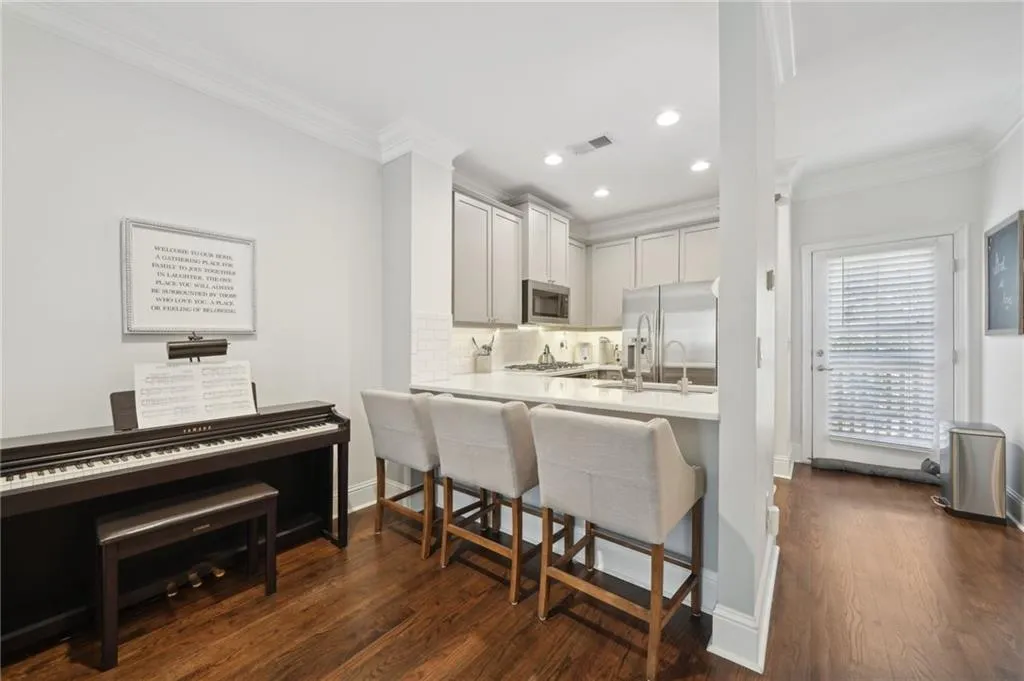 Kitchen featuring crown molding, a breakfast bar area, tasteful backsplash, appliances with stainless steel finishes, and dark wood-style floors