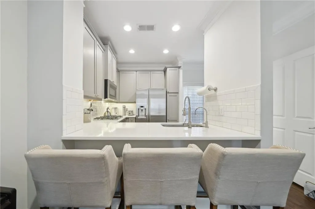 Kitchen with crown molding, stainless steel appliances, decorative backsplash, a sink, and a peninsula