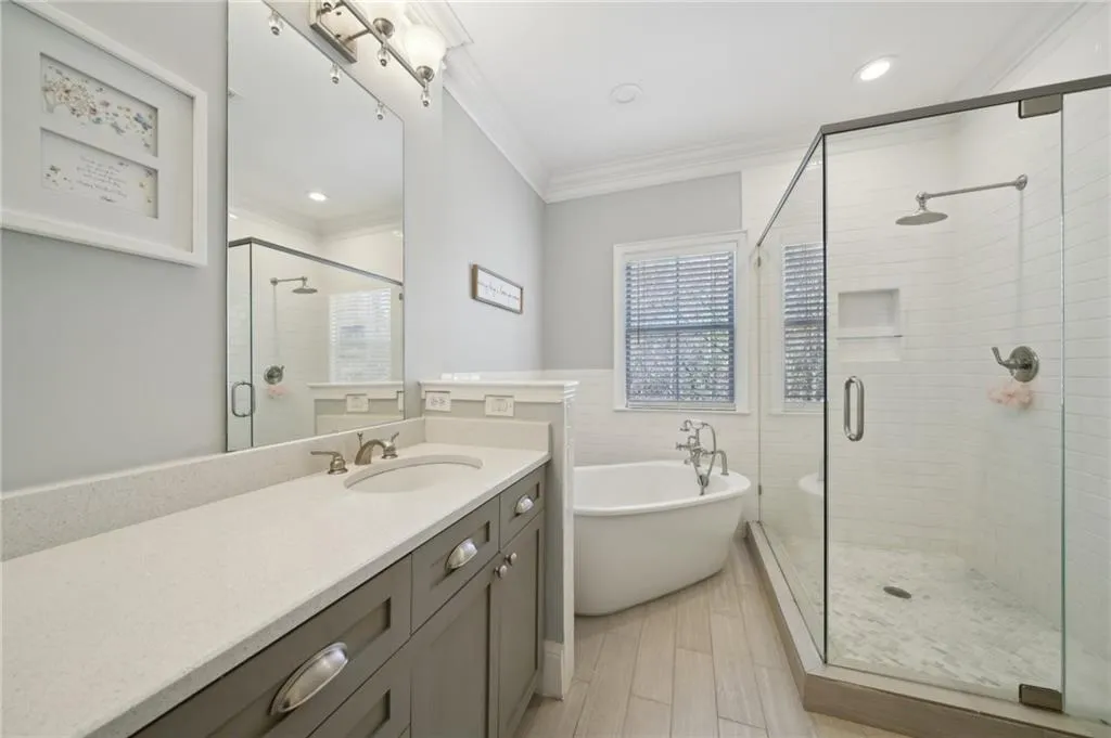 Full bath featuring a stall shower, crown molding, a freestanding tub, and vanity