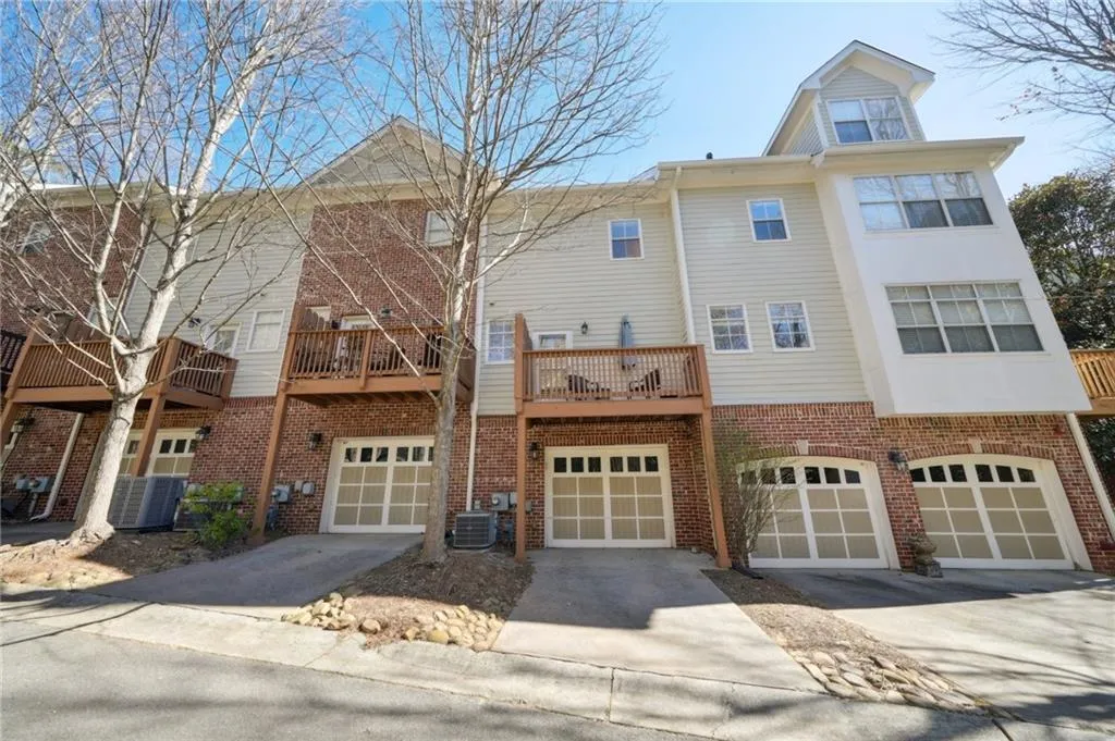 Townhome / multi-family property with central AC unit, driveway, an attached garage, and brick siding