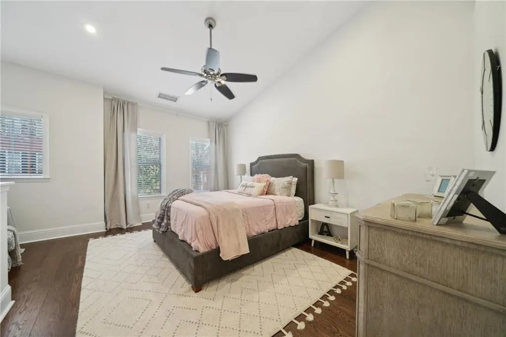 Bedroom with vaulted ceiling, baseboards, ceiling fan, visible vents, and wood finished floors