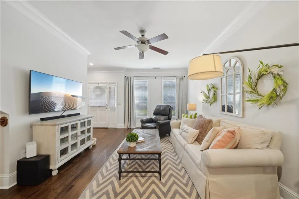 Living area featuring a ceiling fan, ornamental molding, dark wood-type flooring, and baseboards