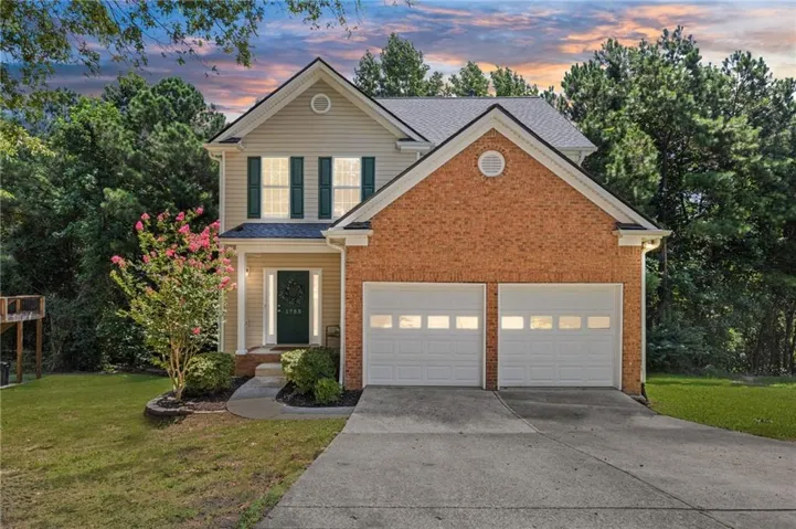 Two-story residence featuring a brick and siding exterior, a two-car garage, and a concrete driveway