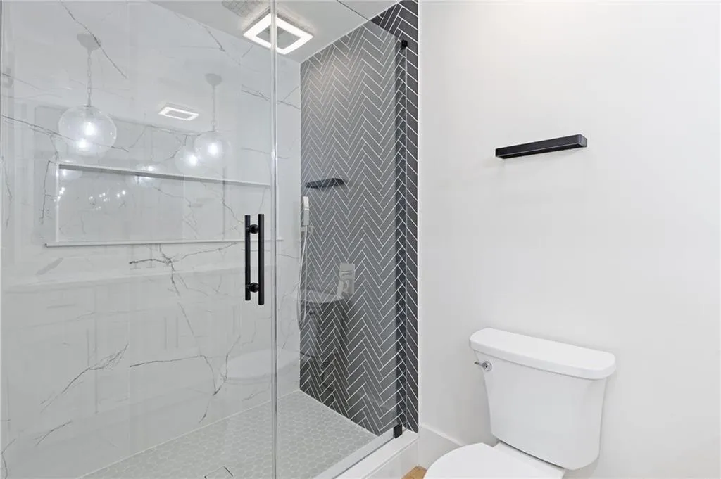 Bathroom with a marble finish shower and toilet
