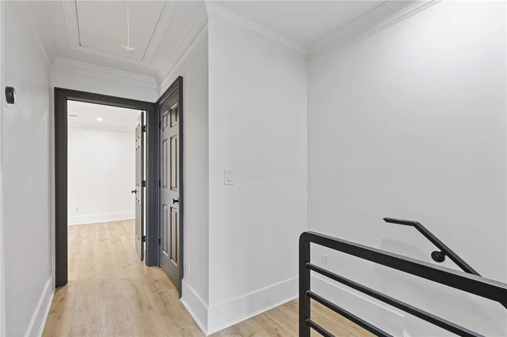 Corridor with attic access, light wood finished floors, ornamental molding, and an upstairs landing