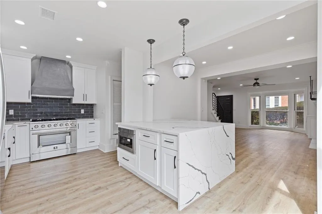 Kitchen with tasteful backsplash, stainless steel appliances, recessed lighting, custom range hood, and white cabinetry