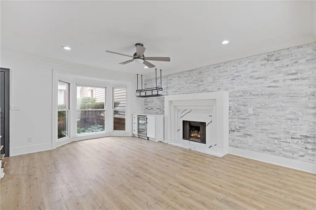 Unfurnished living room with crown molding, light wood-style floors, a ceiling fan, a high end fireplace, and recessed lighting