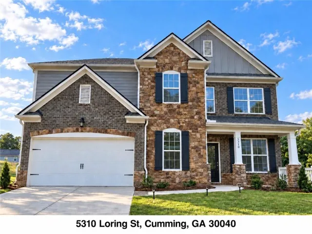 Two-story brick and stone exterior with decorative shutters, white columned front porch, and an attached two-car garage