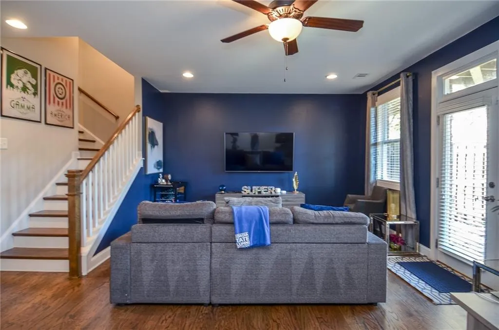 Living area featuring dark wood-type flooring, a ceiling fan, stairs, and recessed lighting