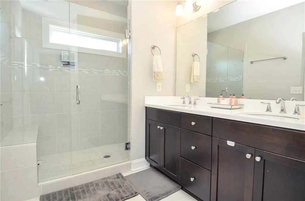 Bathroom featuring double vanity, a shower stall, and light tile patterned flooring