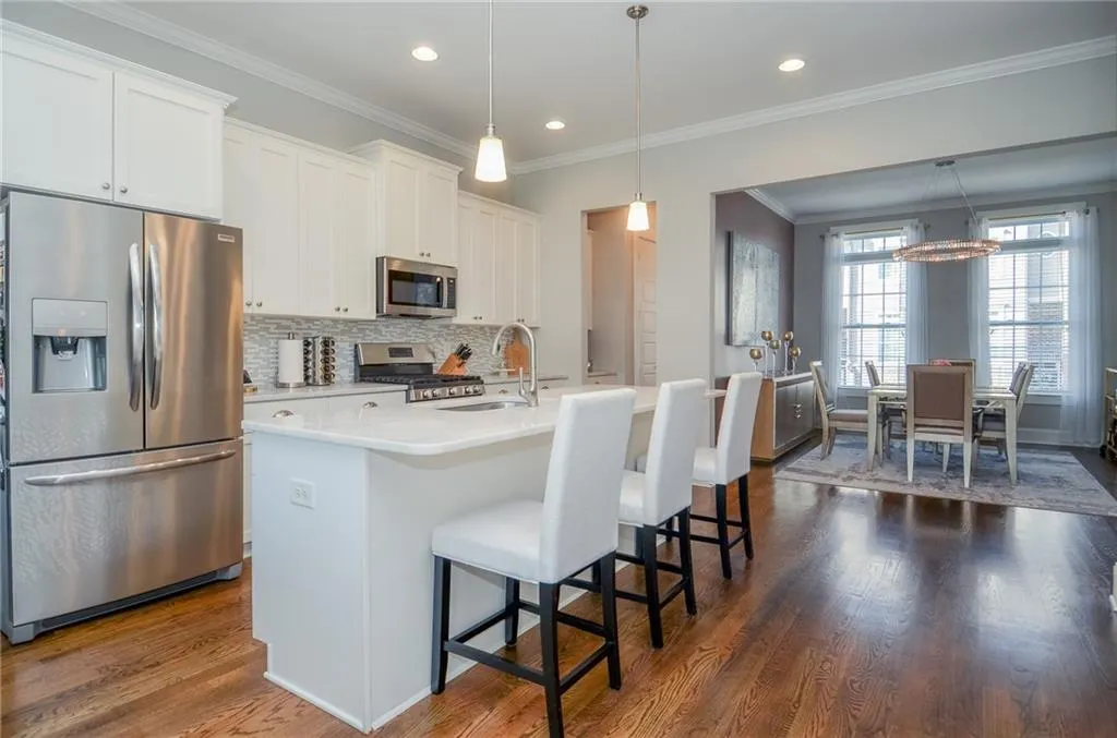 Kitchen featuring appliances with stainless steel finishes, a breakfast bar area, dark wood finished floors, ornamental molding, and decorative backsplash