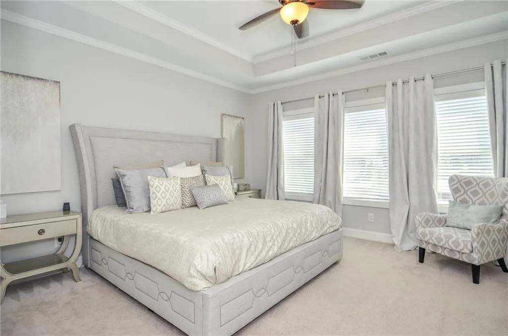 Bedroom featuring carpet floors, a tray ceiling, crown molding, and ceiling fan