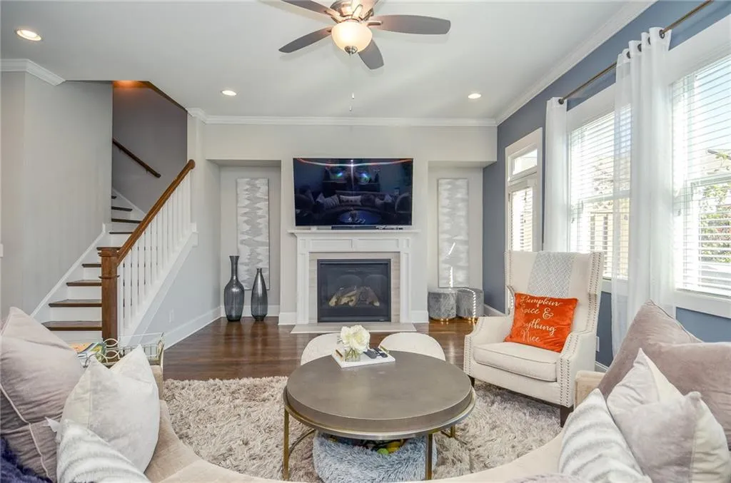 Living room featuring crown molding, stairway, wood finished floors, recessed lighting, and a fireplace with flush hearth