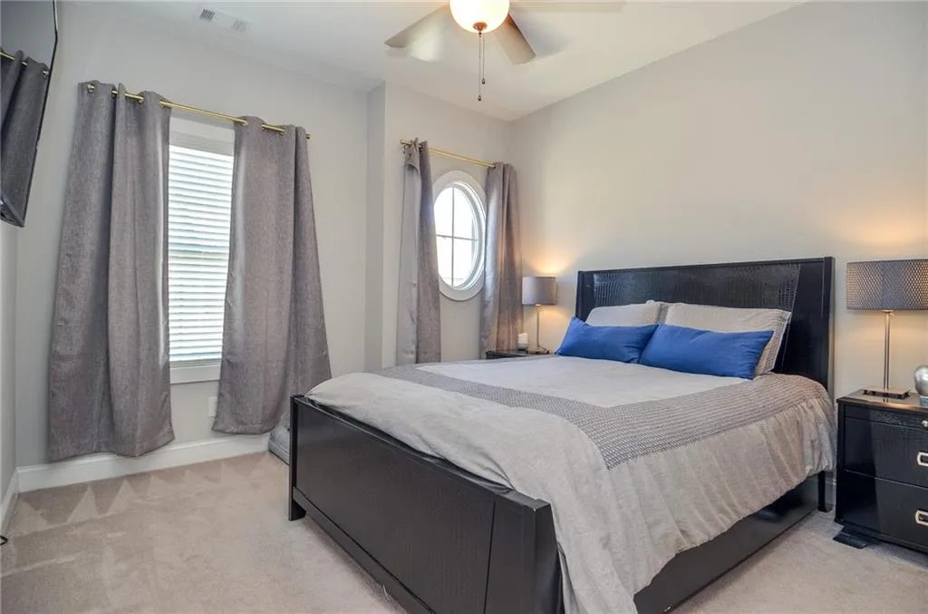 Bedroom with light carpet, multiple windows, and ceiling fan