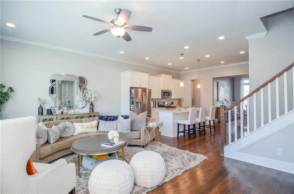 Living room with ornamental molding, dark wood-type flooring, recessed lighting, stairway, and ceiling fan
