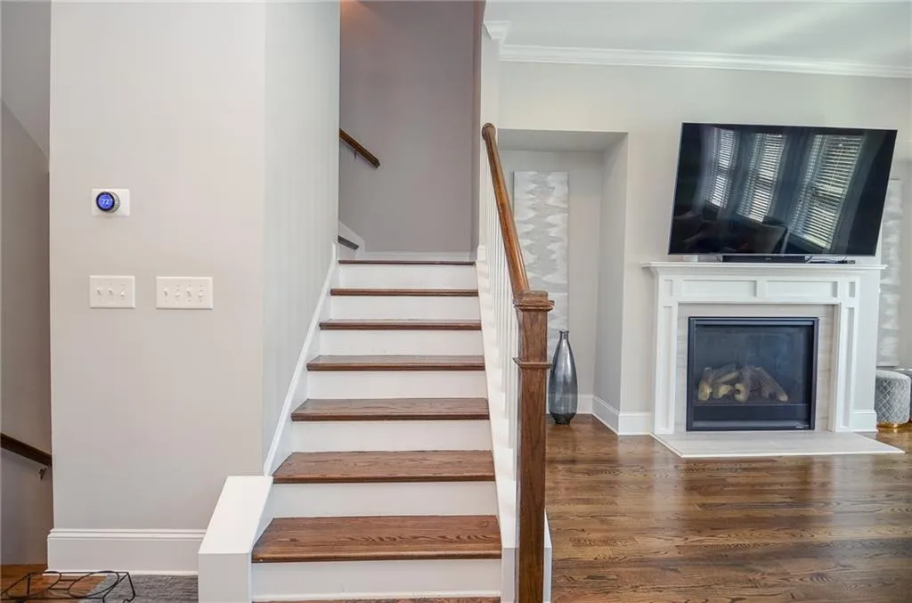 Stairs featuring a glass covered fireplace, ornamental molding, and wood finished floors