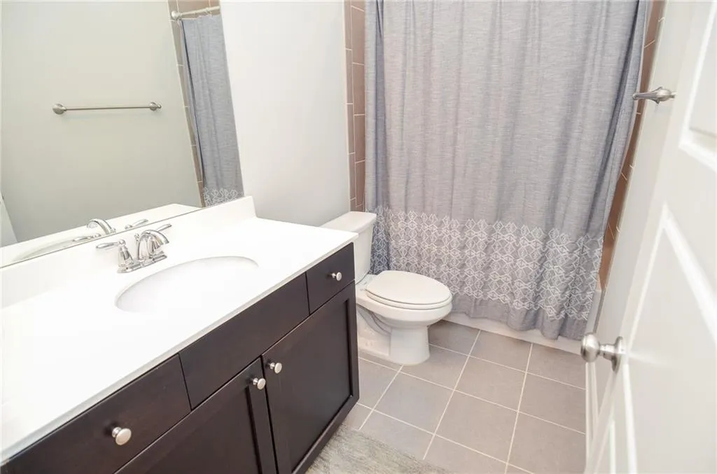 Bathroom featuring vanity, light tile patterned flooring, and shower / tub combo with curtain