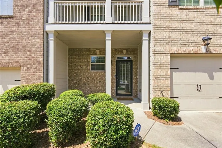 Brick exterior with a covered entry, upper-level balcony, and attached garage