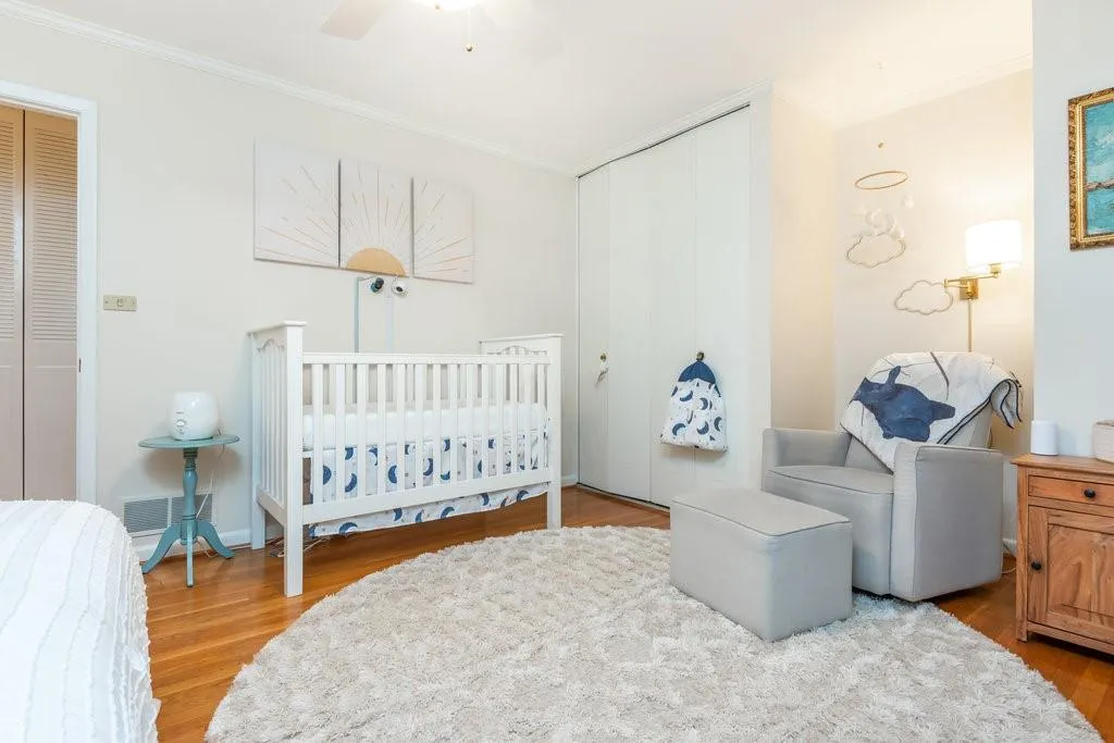 Bedroom with light hardwood / wood-style floors, ceiling fan, a closet, and a crib