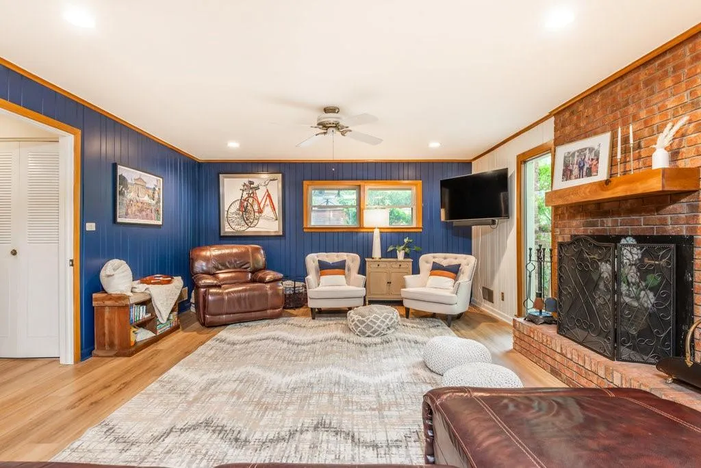 Living room with crown molding, ceiling fan, light hardwood / wood-style flooring, and a brick fireplace