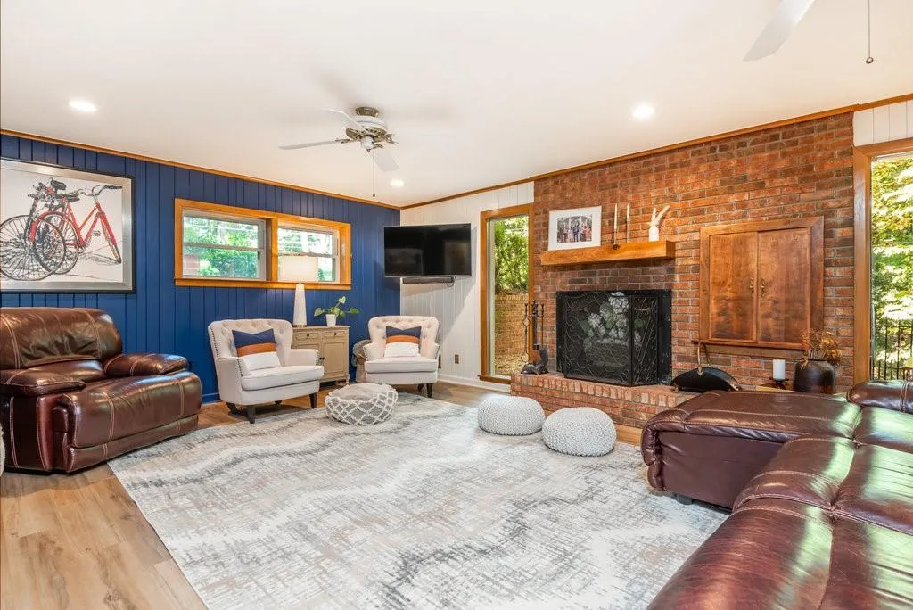 Living room with light hardwood / wood-style flooring, plenty of natural light, a brick fireplace, and ceiling fan