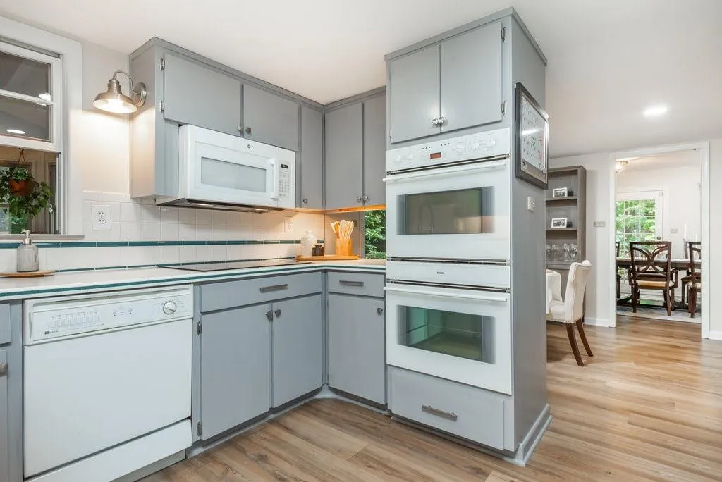 Kitchen featuring gray cabinetry, tasteful backsplash, white appliances, and light hardwood / wood-style floors