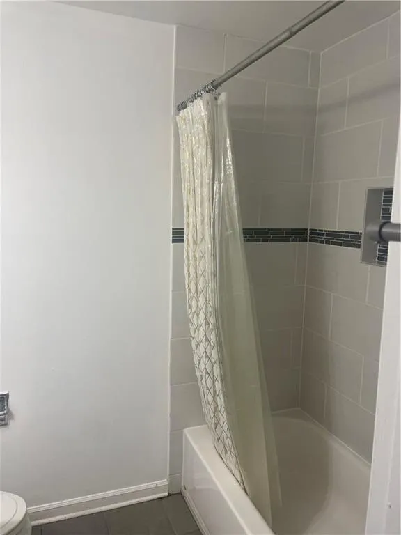 Full bath with shower / bathtub combination with curtain and dark tile patterned floors