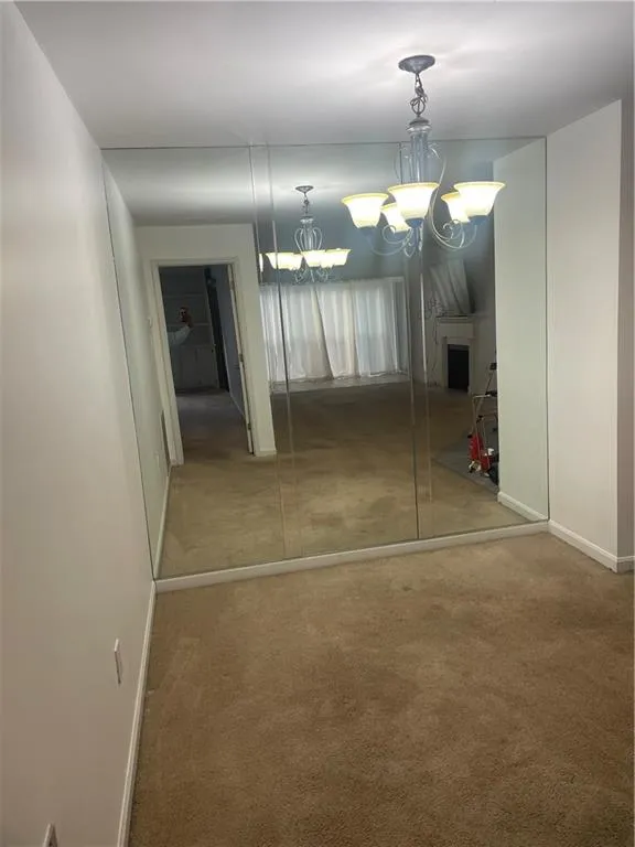 Unfurnished dining area with light colored carpet and a chandelier