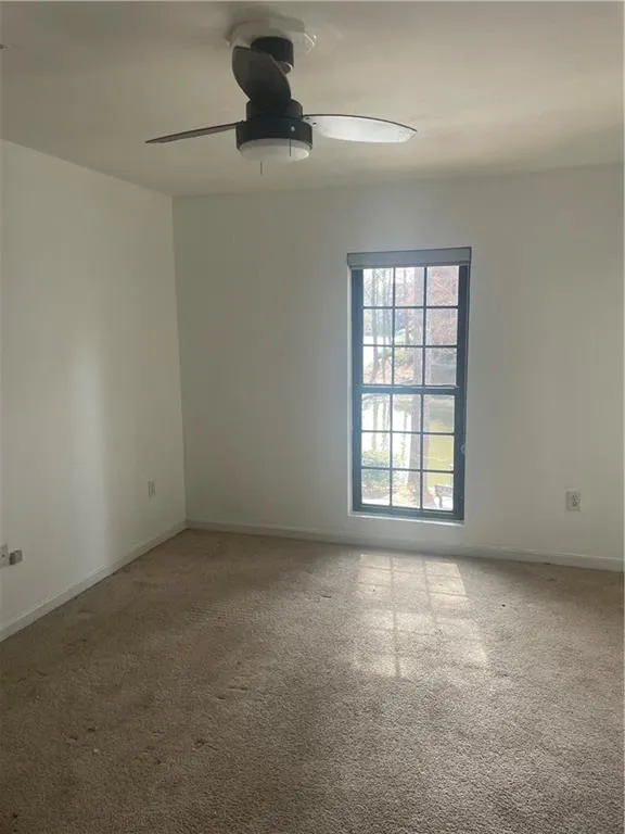 Carpeted spare room with baseboards and ceiling fan