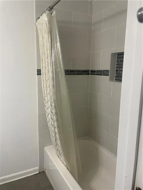 Full bathroom featuring shower / bath combination with curtain and dark tile patterned floors