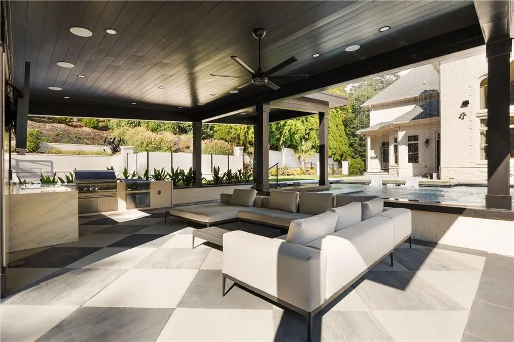 Covered outdoor living space with integrated outdoor kitchen, ceiling fan, recessed lighting, and checkerboard patio pavers
