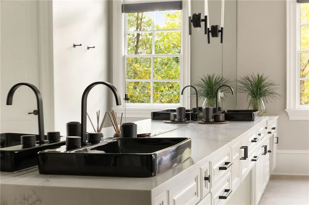Dual black vessel sinks on an expansive vanity, freestanding soaking tub, and a shower with dark-framed glass doors