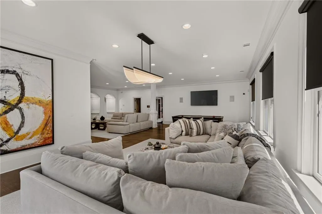 Spacious open-concept living area featuring multiple seating zones with gray upholstered furnishings, recessed ceiling lighting, and pendant fixtures