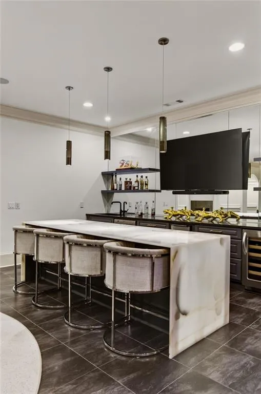 Waterfall-edge island with seating, built-in shelving, integrated beverage refrigerator, and dark-toned floor tiles