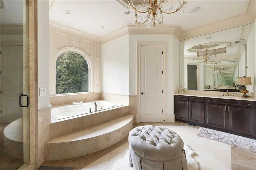 Soaking tub set into a tiered stone surround with an arched window