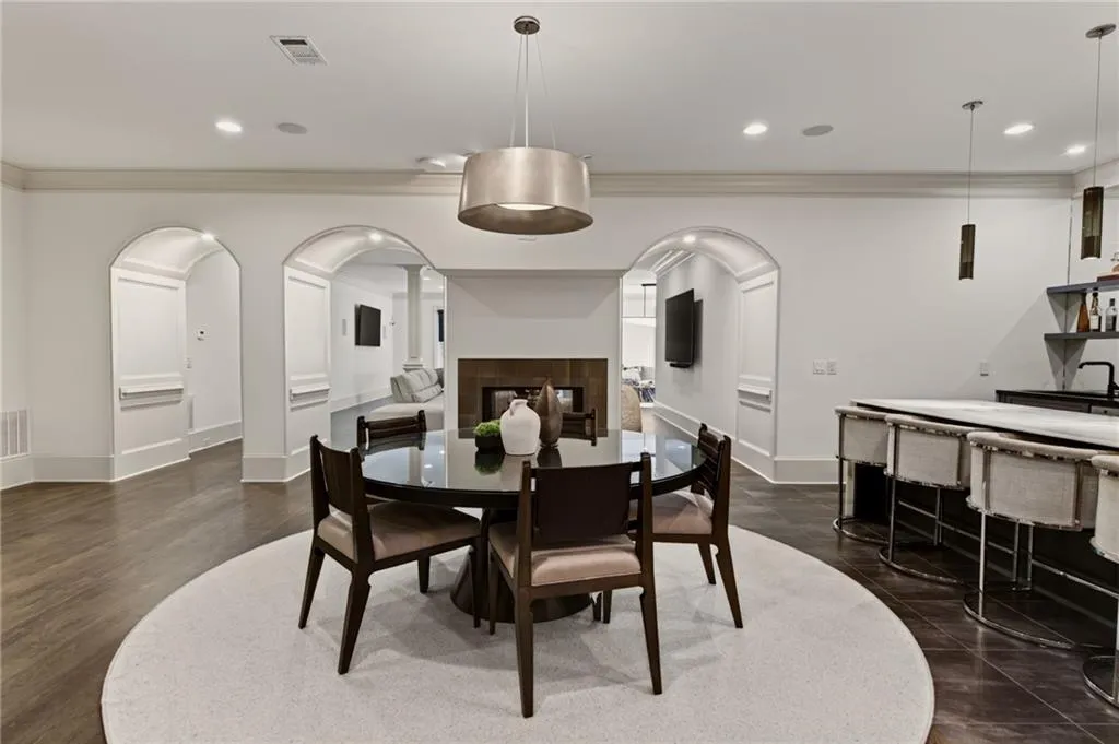 Arched doorways, recessed lighting, and a built-in wet bar with pendant lighting and open shelving