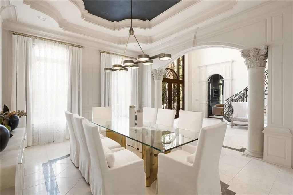 Coffered ceiling with a dark inset, decorative archways, ornate columns, and tile flooring with a contrasting border
