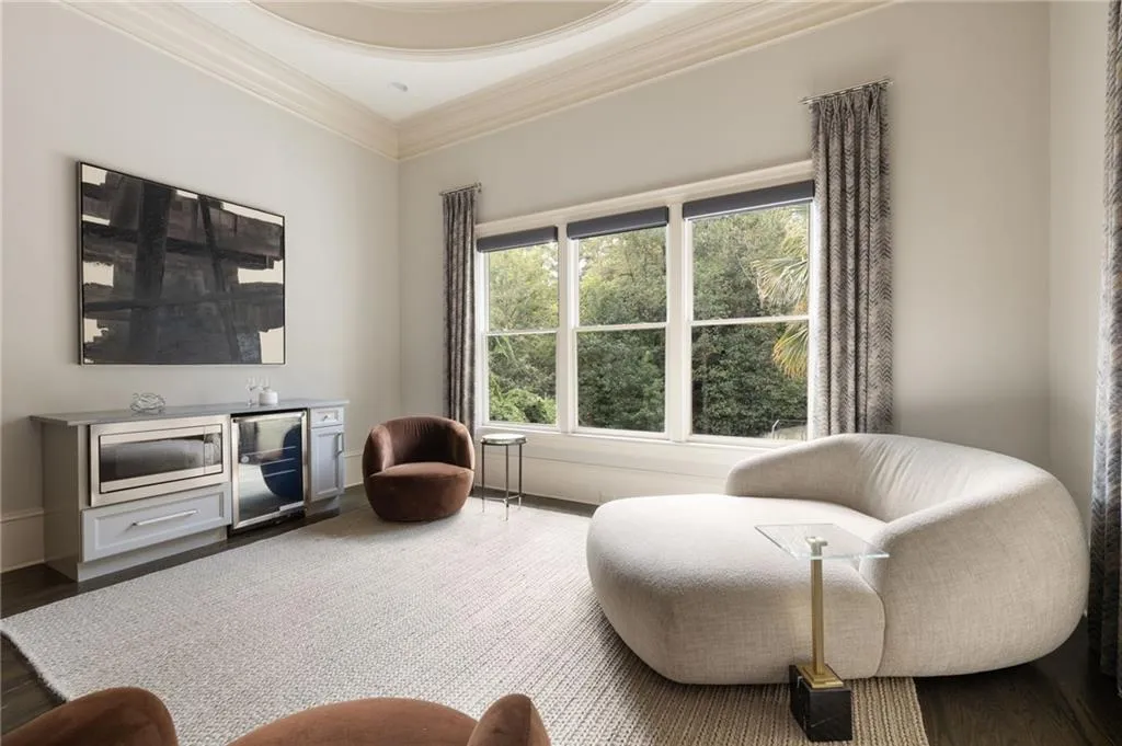 Built-in cabinetry featuring a beverage cooler and microwave drawer, triple window with roller shades, decorative ceiling detail, crown molding, and wood-finish flooring