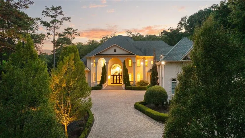 Stately exterior with a columned portico, arched entry, and a paver driveway