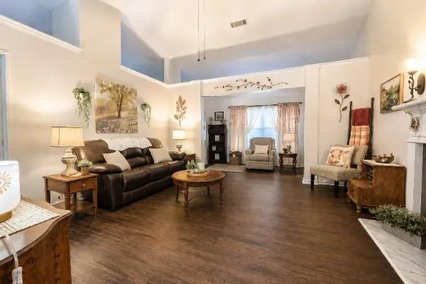 Spacious living area featuring high vaulted ceilings, crown molding, wood-finish flooring, and an archway leading to an additional space