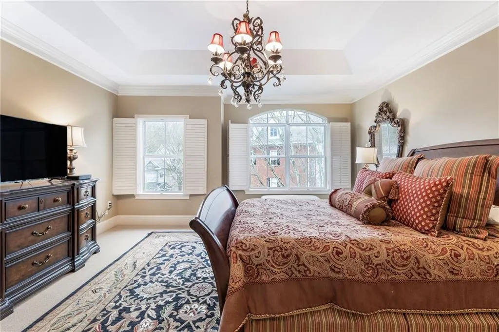 Bedroom with ornamental molding, a chandelier, multiple windows, and light colored carpet