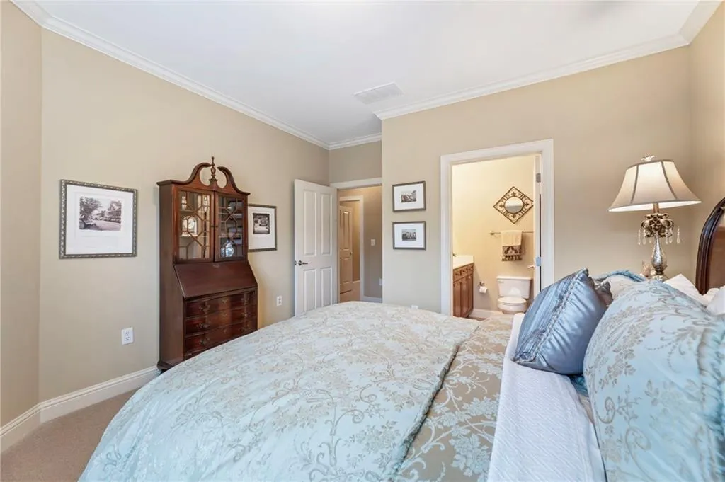Bedroom featuring ornamental molding, light colored carpet, and connected bathroom