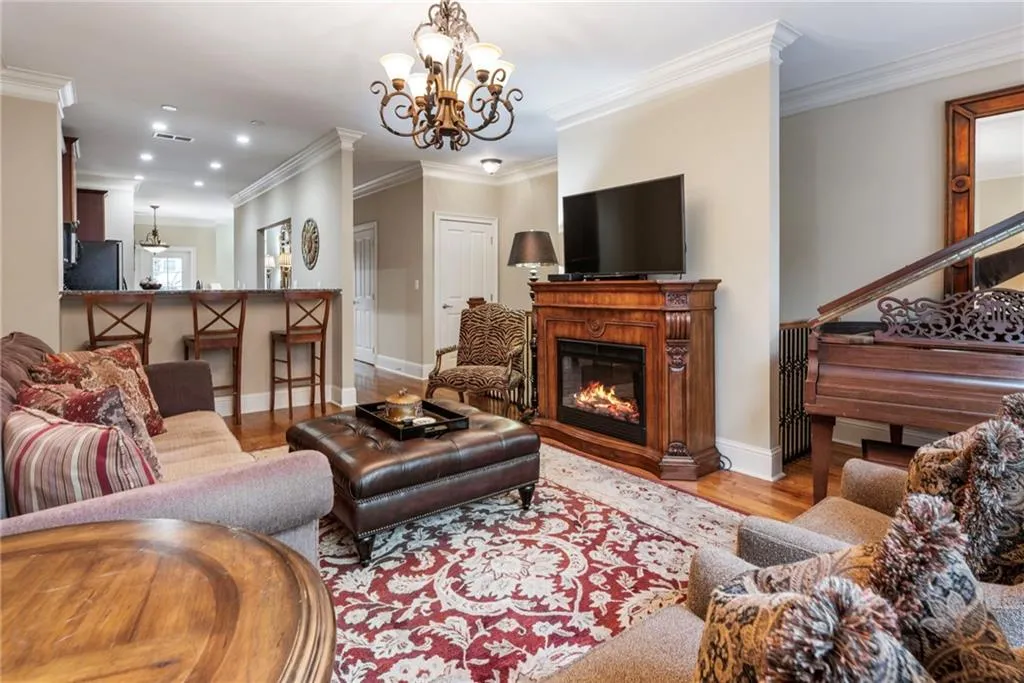 Living area with hanging lights, ornamental molding, light wood finished floors, and a glass covered fireplace
