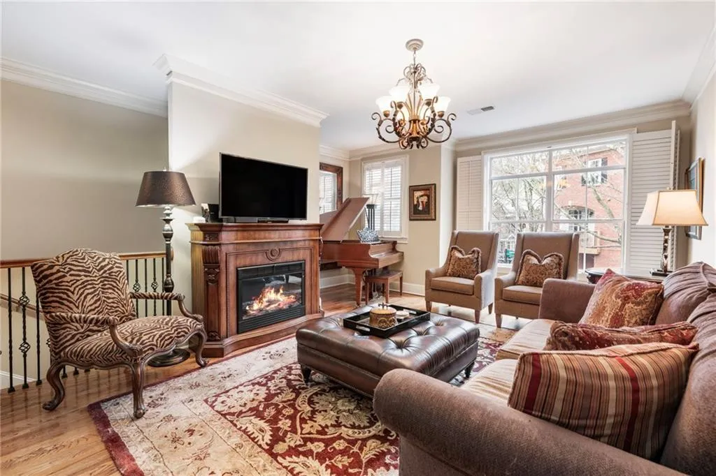 Living area with crown molding, a glass covered fireplace, light wood-type flooring, and hanging lights