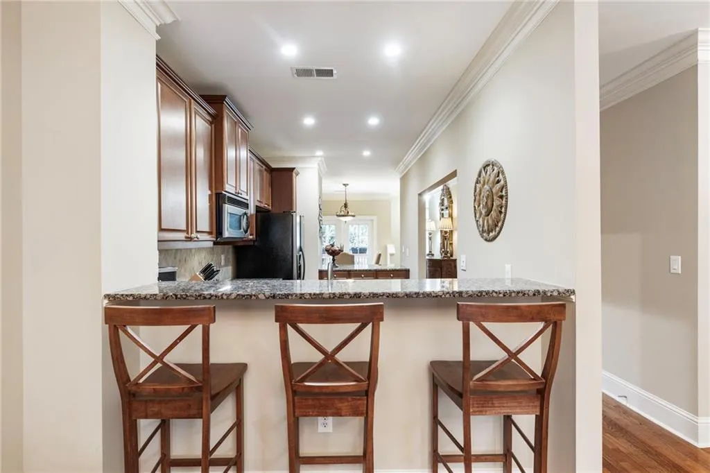 Kitchen with a kitchen bar, dark stone counters, crown molding, a peninsula, and decorative backsplash