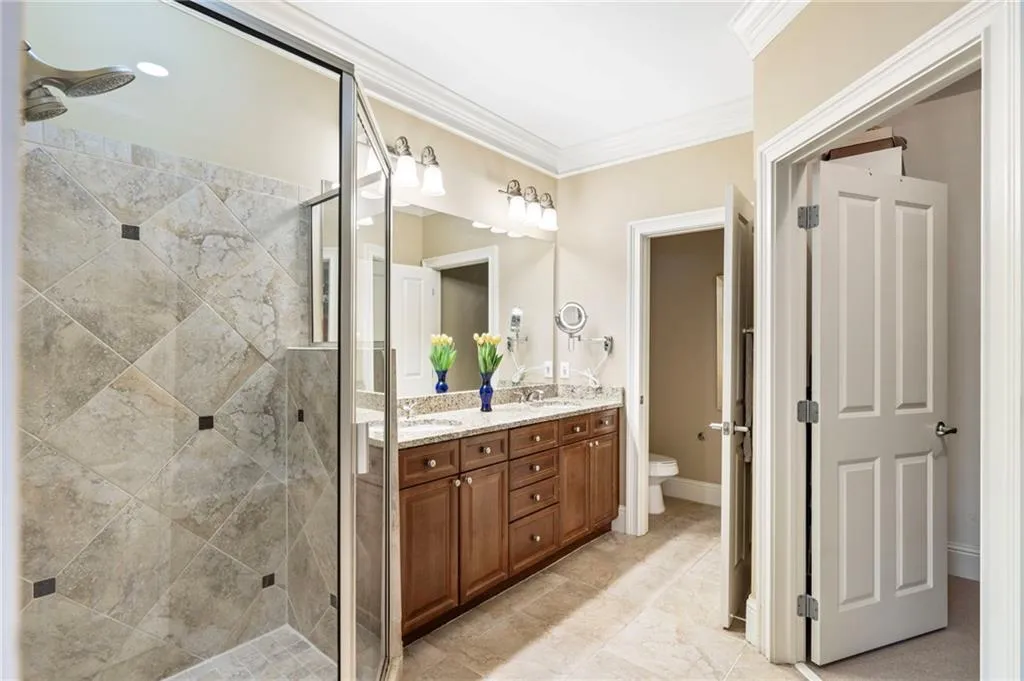 Full bath featuring double vanity, ornamental molding, and a stall shower